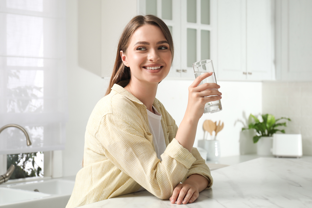 woman holding glass of water in kitchen